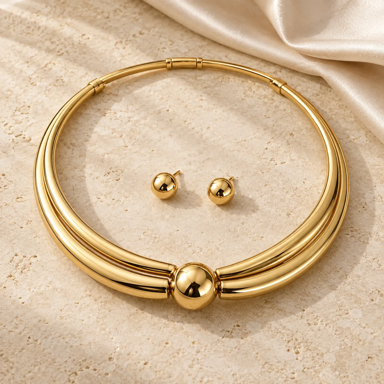 Jewellery collection - one sculptural yellow-gold torque necklace formed from two curved tubular arcs joined by a smooth offset spherical front closure, two matching small spherical gold studs