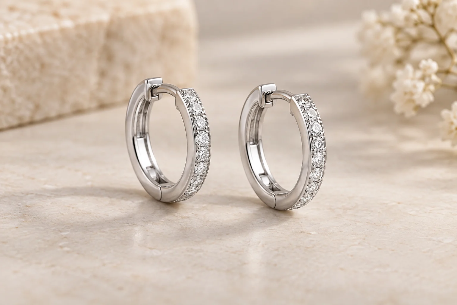 Diamond Earrings editorial - two white-metal flowerless circular huggie earrings with straight continuous tiny round clear-stone channels along the outer edge and visible.