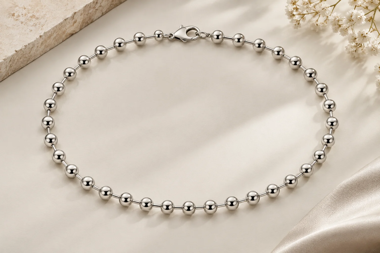 Silver Chains editorial - one polished silver chain constructed exclusively from smooth round linked spheres of equal size joined by short rods, clear true ball chain.